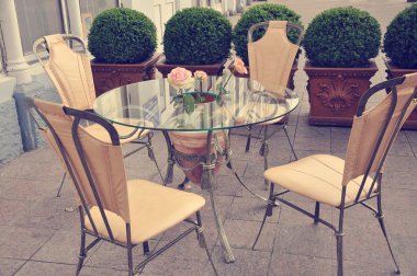 Civarı çiçekli sokakta cam masa sandalye