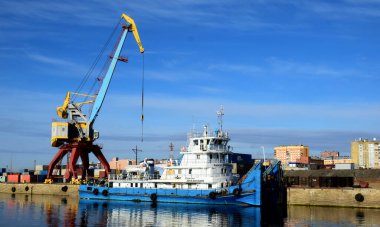 Yenisei nehri üzerinde Dudinka limanının rıhtımına yakın güzel beyaz ve mavi nehir mavnası taşıyıcısı. Arka planda da bir vinç var.