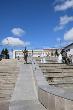 Yenisei, Khatanga, Angara, Mana, Bazaiha nehirlerini çevreleyen binaların arka planında tasvir eden heykellerle Krasnoyarsk şehir merkezindeki çağlayan çeşmenin fotoğrafı