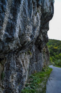 Dik kaya oluşumu, Romanya 'nın Gorj ilçesindeki Sohodol Vadisi (Cheile Sohodolului), Valcan Dağları' ndaki doğal manzaradan geçen bir yol ile aşınmış taş duvar