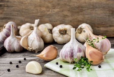 Ahşap bir masada sarımsak, kekik ve siyah biber dalı. Bir demet taze sarımsak, soyulmuş karanfil..