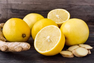 Sarı, olgun limonlar, koyu renkli, eski, ahşap bir arka planda zencefil kökü. Yakın plan..