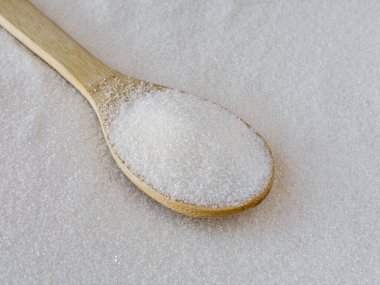 Tahta kaşıkta beyaz granüllü şeker ve şeker. Üst görünüm.