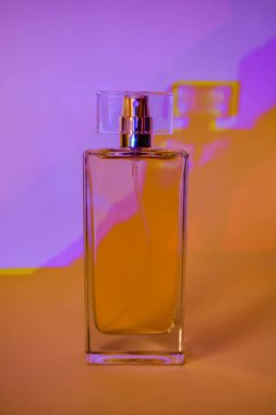 Çok renkli neon gölgelerin arka planına karşı şişedeki parfüm. Yakın plan..