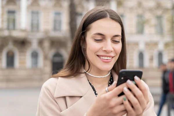 Retrato Una Mujer Encantadora Mirando Teléfono Inteligente Con Sonrisa Pie — Foto de Stock