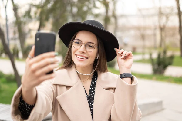 Jovem Encantadora Tirando Selfie Segurando Smartphone Preto Sorrindo Vestindo Chapéu Fotos De Bancos De Imagens