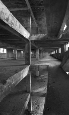 Terk edilmiş eski bir beton salonun içinde. Birkaç katı ve zeminde bir delik olan dağınık bir sanayi deposu..