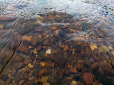 Hızlı derenin soyut samimi manzarası, temiz şeffaf sığ su akıntısı ve dipteki taşlardan oluşan dalgalanan su yüzeyi