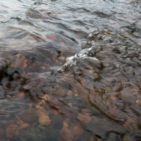 Shallow abstract turbulent water motion, fast stream current over stones, small surge on surface, natural forces