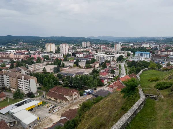 Bulutlu bir yaz günü, Doboj kasabası ve kasabanın üstündeki tepedeki Gradina kalesinden gelen dağlık arazi manzarası.