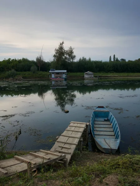 Landscape of Sava river with fishing boats and huts during summer overcast day