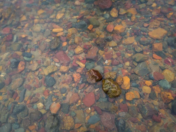 Two wet stones in shallow water and colorful underwater stones, abstract landscape