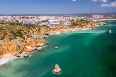 Lagos, Algarve, Portekiz 'deki Dona Ana Sahili. Portekiz 'in güneyindeki altın sahil kayalıkları. Arka planda şehir olan hava manzarası. Camilo ve pinhao plajı..