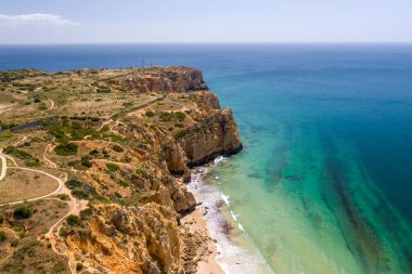 Lagos, Algarve, Portekiz 'deki Canavial Plajı. Portekiz 'in güneyindeki altın sahil kayalıkları. Güneşli bir günde hava manzarası. Arka planda Ponta da Piedade. Deniz feneri. Turkuaz Atlantik Denizi.