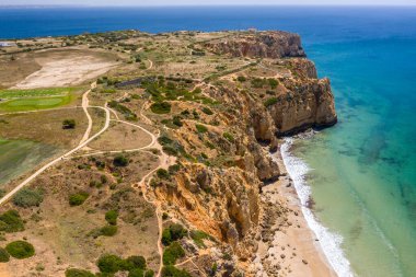 Lagos, Algarve, Portekiz 'deki Canavial Plajı. Portekiz 'in güneyindeki altın sahil kayalıkları. Güneşli bir günde hava manzarası. Arka planda Ponta da Piedade. Deniz feneri. Turkuaz Atlantik Denizi.