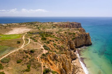 Lagos, Algarve, Portekiz 'deki Canavial Plajı. Portekiz 'in güneyindeki altın sahil kayalıkları. Güneşli bir günde hava manzarası. Arka planda Ponta da Piedade. Deniz feneri. Turkuaz Atlantik Denizi.