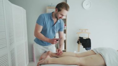 Spa yatağında yatan beyaz bir adam masaj yaptırıyor. Güzellik salonunda kadın masaj terapisti. Sağlık hizmeti vücut masajı spa konsepti.