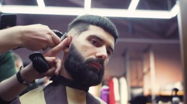 Son moda berber berber dükkanında sakallı adamın saçını kırpıcı ile kesiyor. Kuaförde erkek kuaförü ve saç kesimi. Saçını budayarak mı? Kuaför retro kuaförde saç kesimi yapıyor..