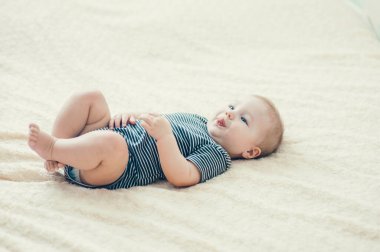 Çocuk yatakta oynuyor, gülümsüyor.