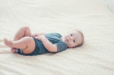 Çocuk yatakta oynuyor, gülümsüyor.