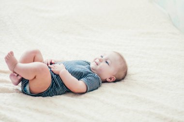 Çocuk yatakta oynuyor, gülümsüyor.