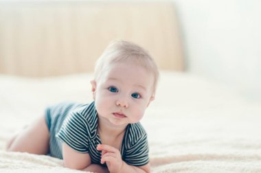 Çocuk yatakta oynuyor, gülümsüyor.