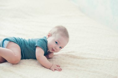 Çocuk yatakta oynuyor, gülümsüyor.