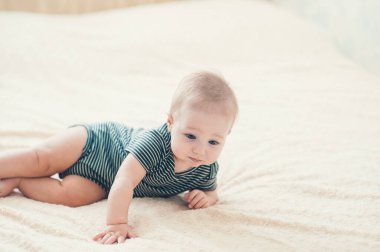 Çocuk yatakta oynuyor, gülümsüyor.