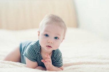 Çocuk yatakta oynuyor, gülümsüyor.