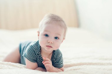 Çocuk yatakta oynuyor, gülümsüyor.