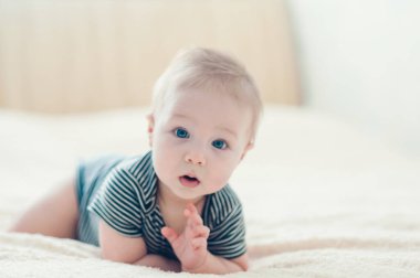 Çocuk yatakta oynuyor, gülümsüyor.