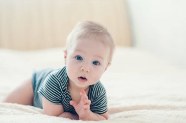 Çocuk yatakta oynuyor, gülümsüyor.