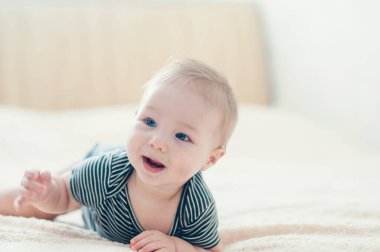 Çocuk yatakta oynuyor, gülümsüyor.