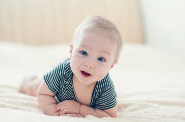 Çocuk yatakta oynuyor, gülümsüyor.