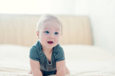 Çocuk yatakta oynuyor, gülümsüyor.