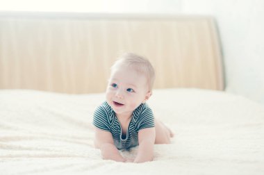 Çocuk yatakta oynuyor, gülümsüyor.