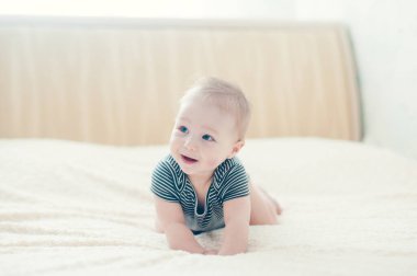 Çocuk yatakta oynuyor, gülümsüyor.