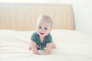 Çocuk yatakta oynuyor, gülümsüyor.