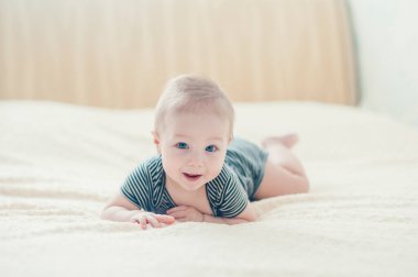 Çocuk yatakta oynuyor, gülümsüyor.