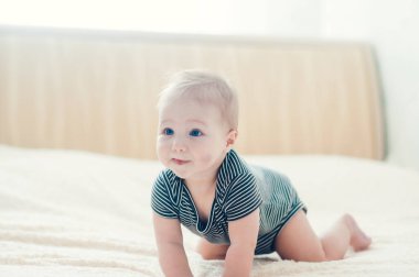 Çocuk yatakta oynuyor, gülümsüyor.