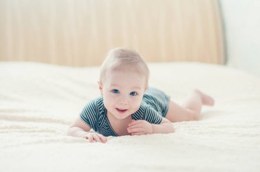 Çocuk yatakta oynuyor, gülümsüyor.