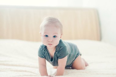 Çocuk yatakta oynuyor, gülümsüyor.