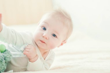 Yakışıklı, neşeli çocuk yatakta emekliyor..