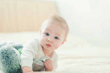 Yakışıklı, neşeli çocuk yatakta emekliyor..