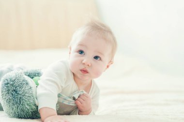 Yakışıklı, neşeli çocuk yatakta emekliyor..