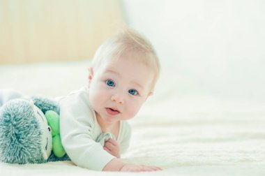 Yakışıklı, neşeli çocuk yatakta emekliyor..