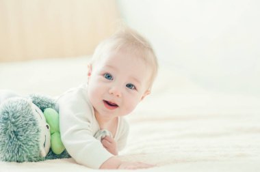 Yakışıklı, neşeli çocuk yatakta emekliyor..