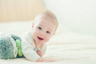 Yakışıklı, neşeli çocuk yatakta emekliyor..