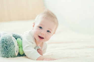 Yakışıklı, neşeli çocuk yatakta emekliyor..