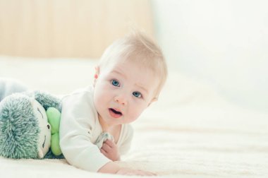 Yakışıklı, neşeli çocuk yatakta emekliyor..